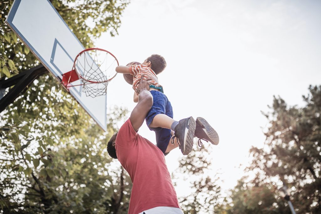 Father and son having fun, playing basketball outdoors